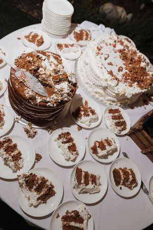Sliced layered chocolate cake with white frosting on plates at a wedding reception dessert table.