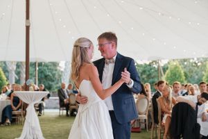 Bride shares a sweet father-daughter dance under a white tent at an outdoor wedding reception.