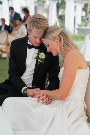Bride and groom sit closely holding hands in an intimate moment during their wedding reception.