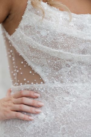 Close-up detail of delicate white lace and beading on an elegant wedding dress bodice.