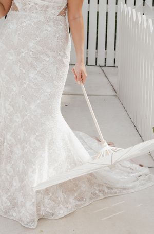Close-up details of an intricate lace wedding dress train against a white walkway.
