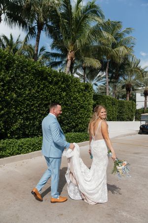 Wedding couple walking together on a palm-lined path in tropical destination setting.