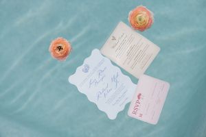Decorative paper fans and wedding rings arranged on a surface with floral arrangements and Corona beer bottles.