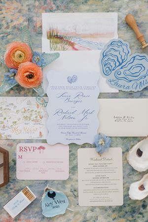 Elegant wedding stationery collection featuring blue and coral details with floral accents on a watercolor background.