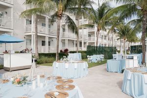 Outdoor wedding reception venue with blue and white decor under palm trees.
