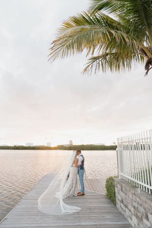 Romantic sunset moment on a waterfront dock with palm fronds framing the scene.