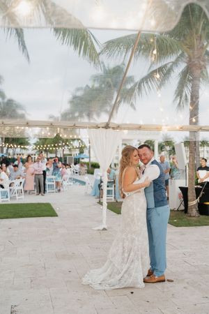 Wedding reception celebration under string lights and palm trees at dusk.