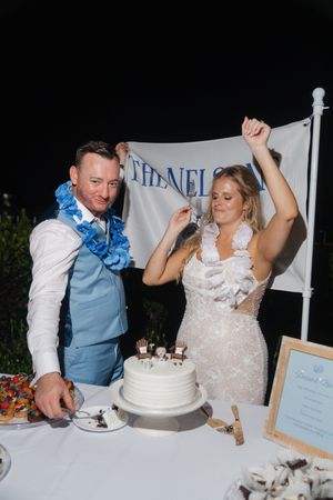 A couple celebrates while cutting their wedding cake at the reception.