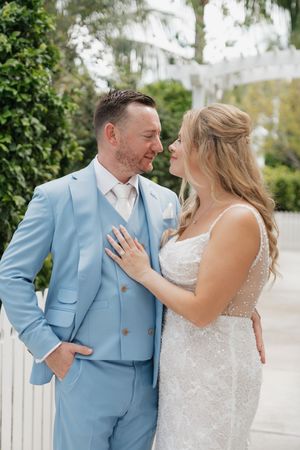 A couple shares intimate moments in their wedding attire featuring a light blue suit and white dress.