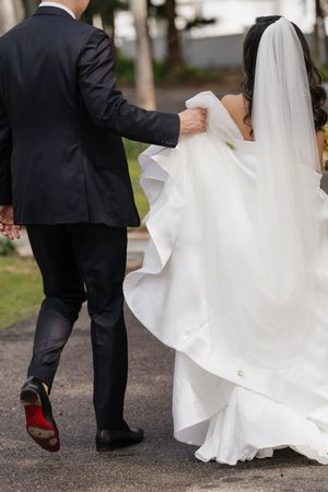 A series of detail shots showing the movement of a wedding dress train and formal shoes on a path.