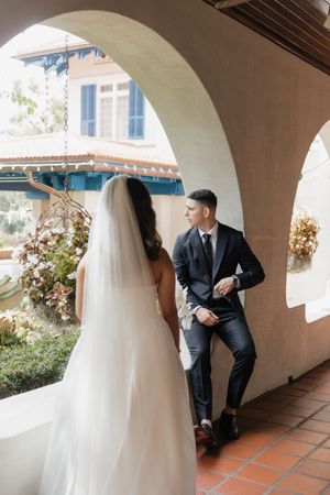 Wedding couple poses under arched walkway with terracotta tiles and stucco walls.