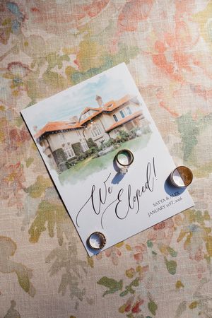 Wedding invitation cards with calligraphy and watercolor details displayed on a textured floral background.