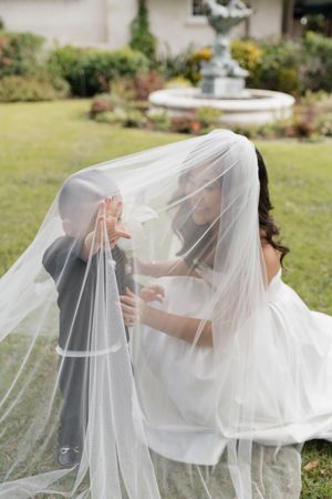 Flowing white wedding veil caught in a gentle breeze across a garden setting.