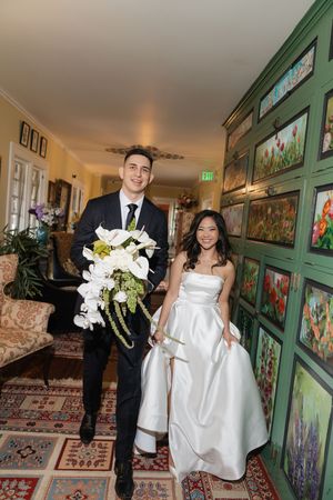Wedding couple walking through elegant hallway with green painted walls and artwork.