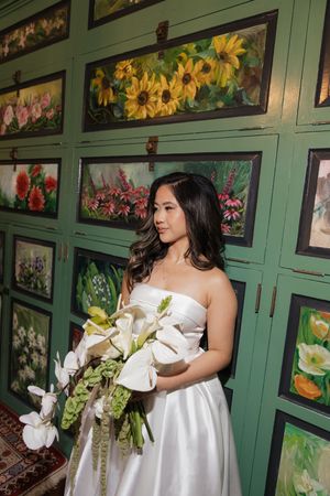Wedding dress details against a backdrop of green cabinets with floral artwork displays.