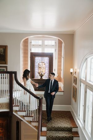 Interior hallway of classic venue with stained glass windows and elegant staircase during wedding preparations.
