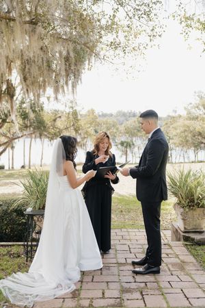 A series of romantic first look photos showing a couple in wedding attire on a stone patio surrounded by Spanish moss.