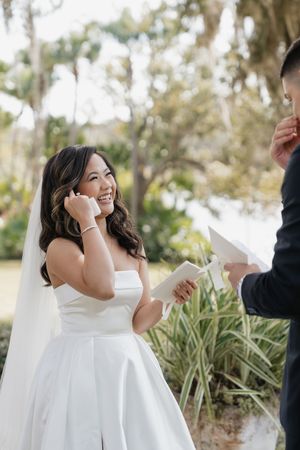 Wedding ceremony moment in an outdoor garden setting with white dress and floral decor.