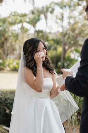 Emotional wedding ceremony moment captured in a garden setting with Spanish moss trees.