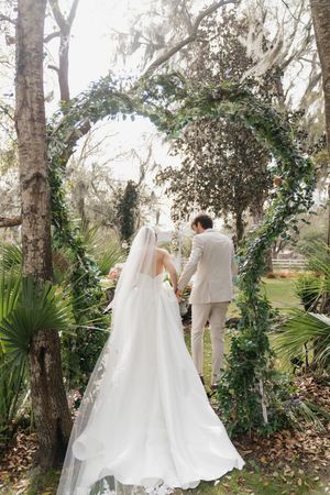 A romantic wedding photoshoot among moss-draped trees and lush greenery in a natural setting.