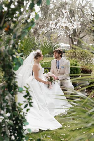 A dreamy garden wedding scene with palm fronds and greenery framing an intimate moment.