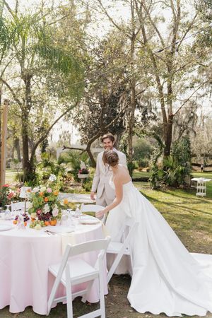 A couple enjoying their wedding reception at an elegantly decorated outdoor table with colorful floral arrangements.
