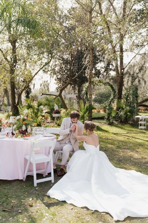 A couple shares an intimate moment at their garden wedding reception with pink table linens and natural decor.