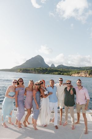Group of friends posing on a yacht deck with stunning St. Lucia Piton mountains in the background.