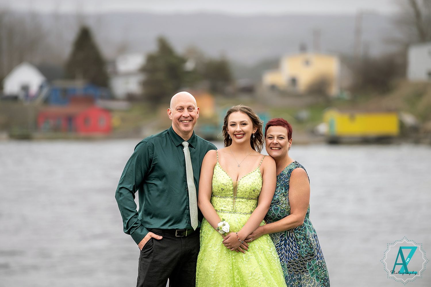 A formal group photo by a lake with a lime green dress and dark green shirt.