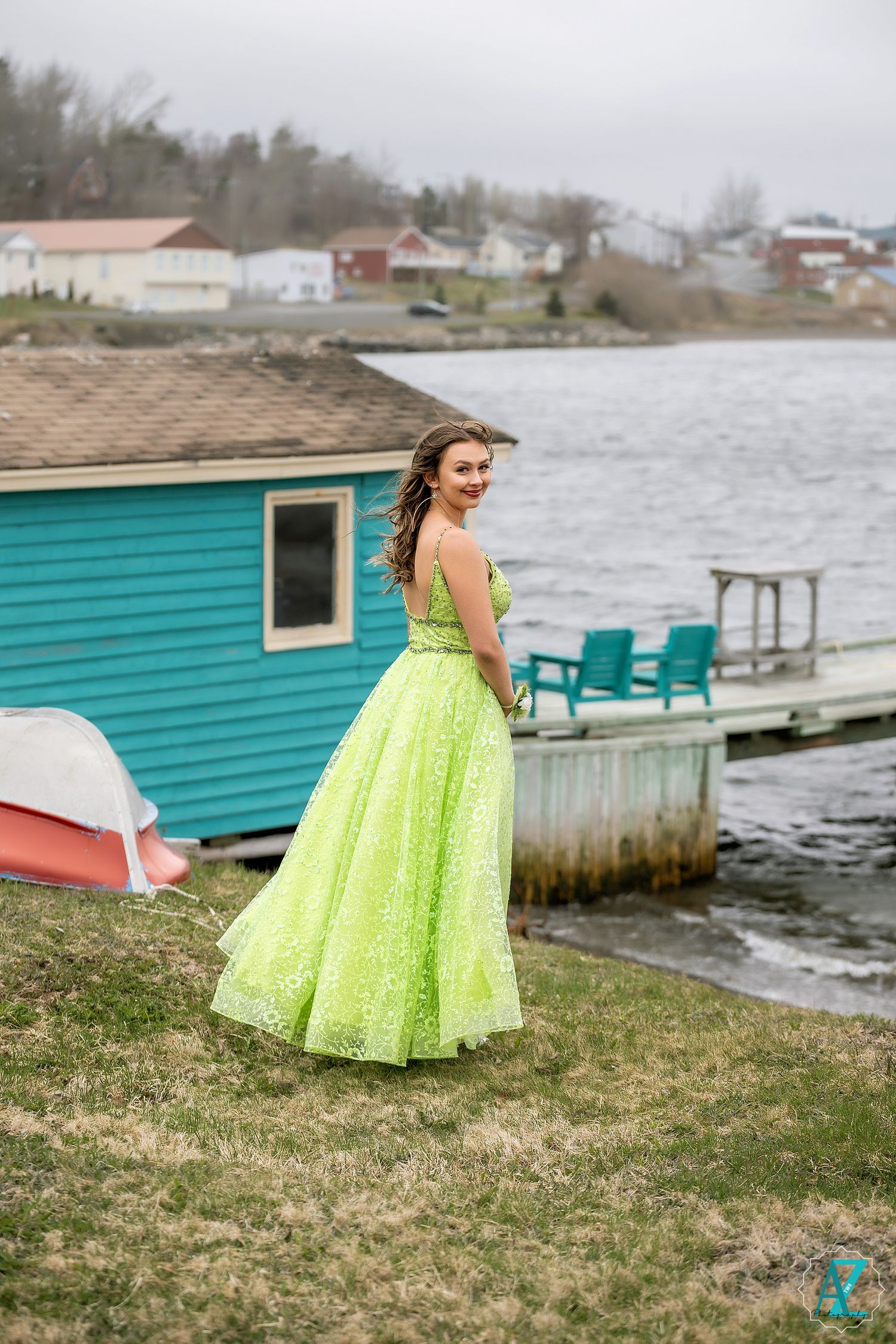 A lime green formal gown stands out against a teal boathouse and waterfront setting.