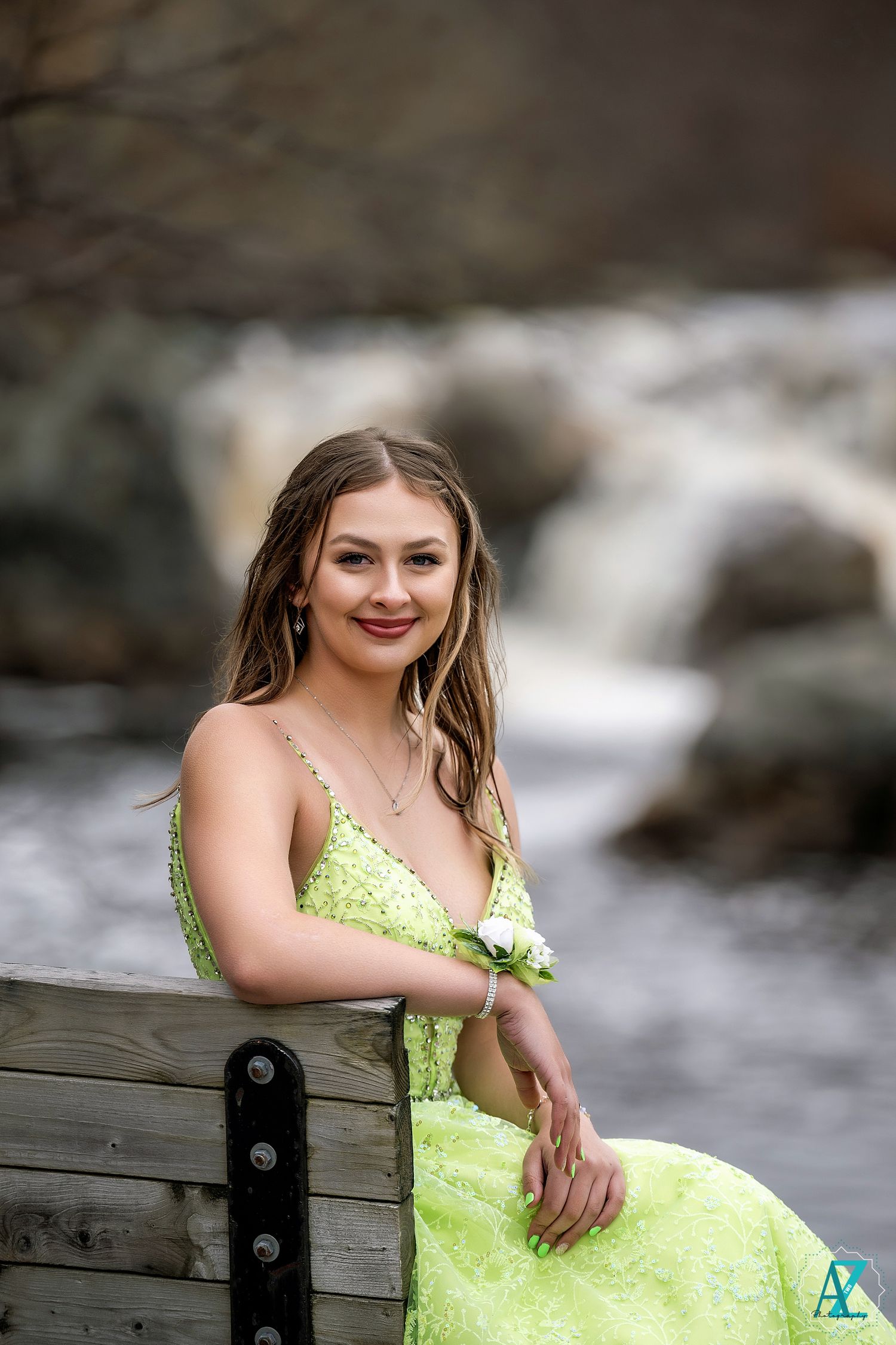 A sparkly lime green formal dress contrasts with rushing water and rocks in nature setting.