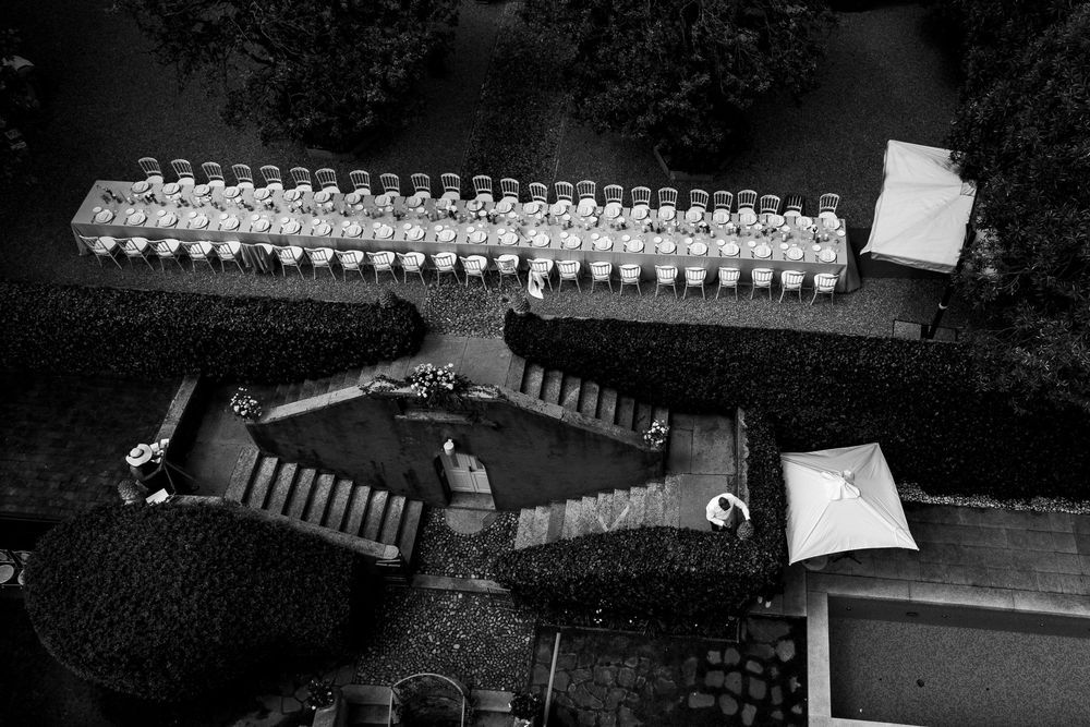 Aerial black and white view of people arranged in uniform rows with tents and structures on a lawn.