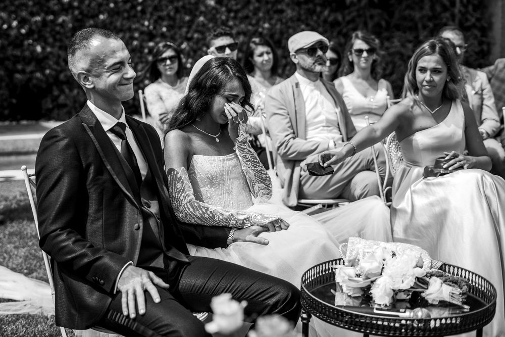 A candid black and white moment at an outdoor party with guests gathering around refreshments and treats on a table.