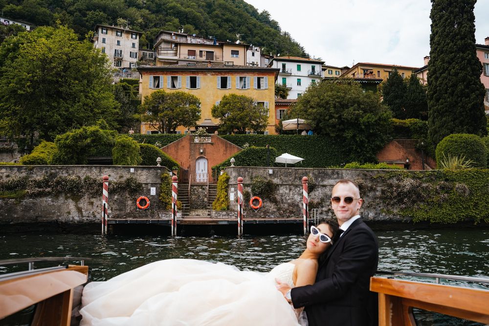 People enjoying a scenic boat ride along Lake Como in Italy with historic villas and buildings on the hillside.