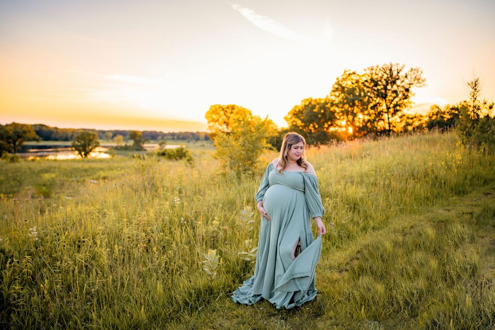 A serene maternity photo shoot in a golden field during sunset.
