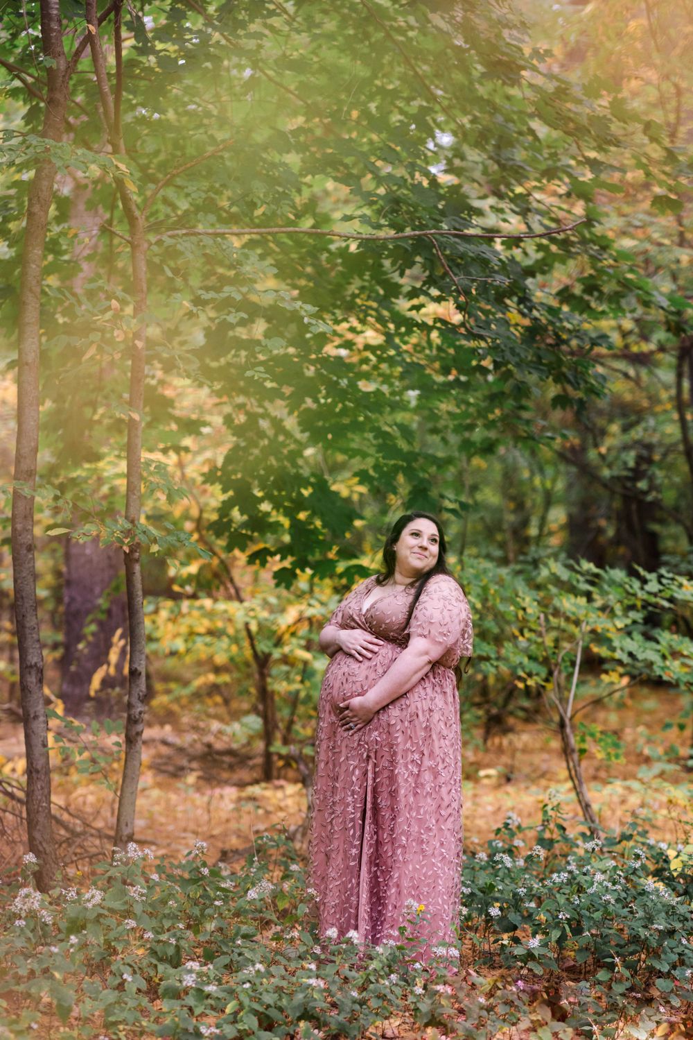 A serene maternity moment captured in a wooded setting with warm autumn colors.