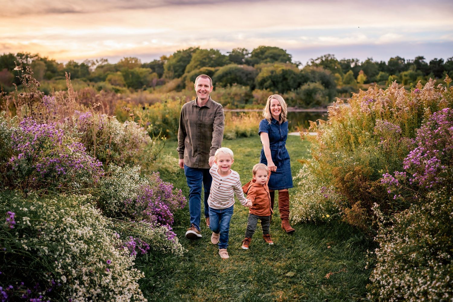 A family sitting together on a blanket in a grassy field during golden hour.
