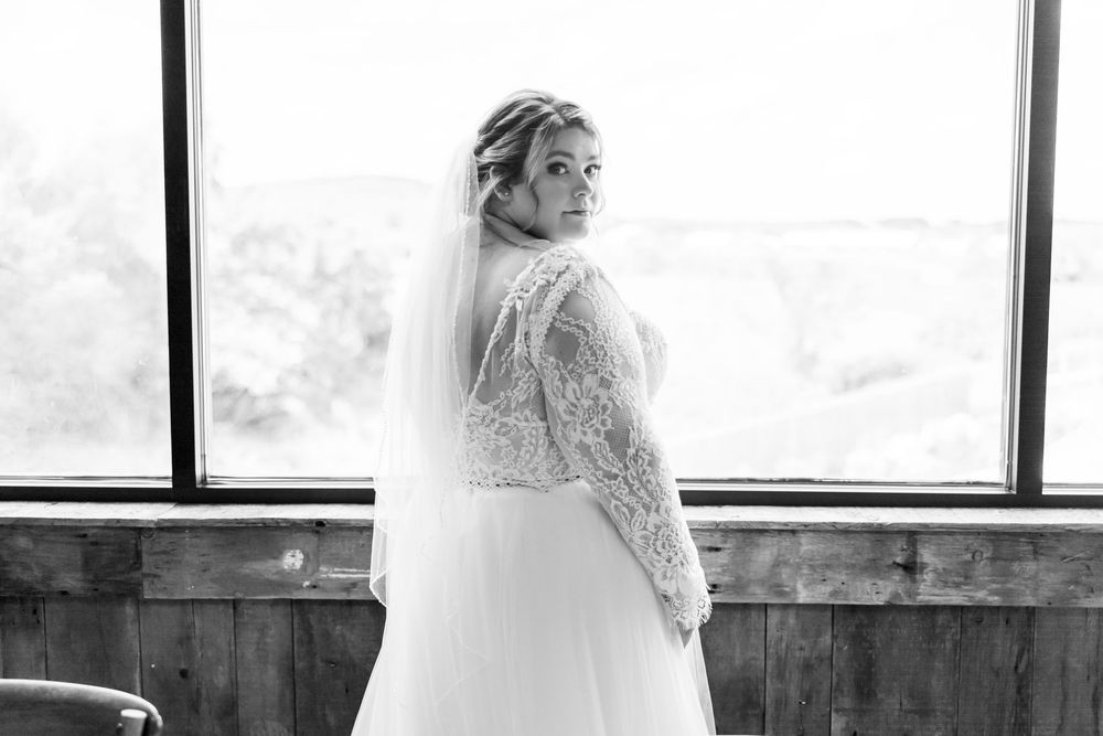 Beautiful bridal portrait in lace wedding dress by window with elegant natural lighting.