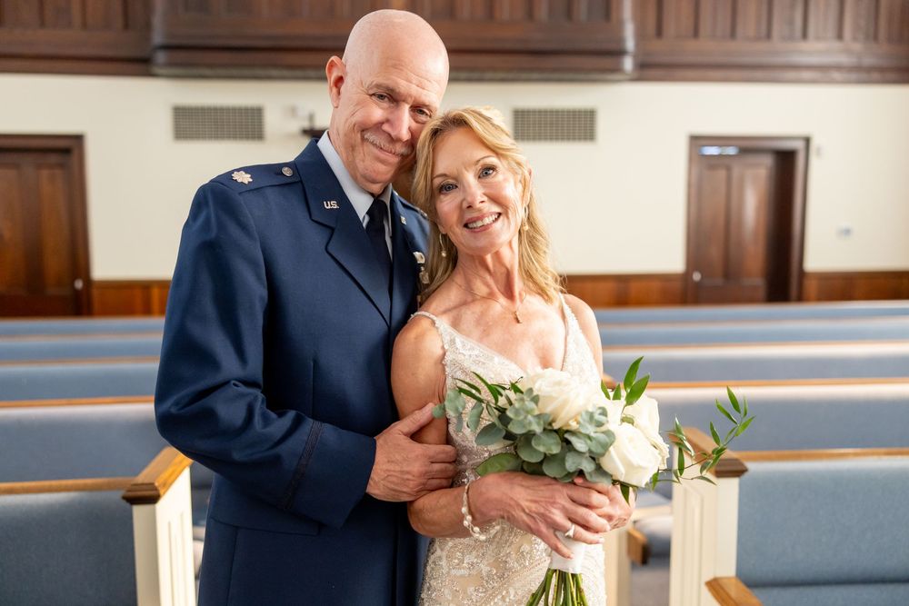 People celebrate their wedding ceremony in a church with white flowers and dark suits.