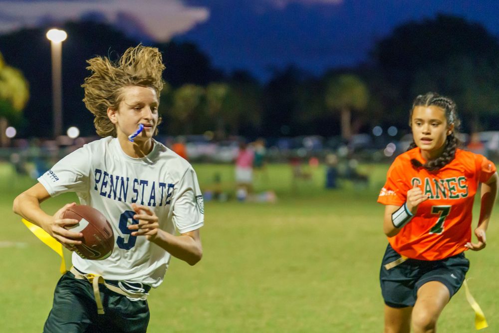 oung kids football player running with ball during youth game, action-packed sports photography by SRX Media Group