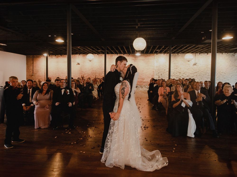 A romantic first dance at an industrial-style wedding reception venue with exposed brick walls.