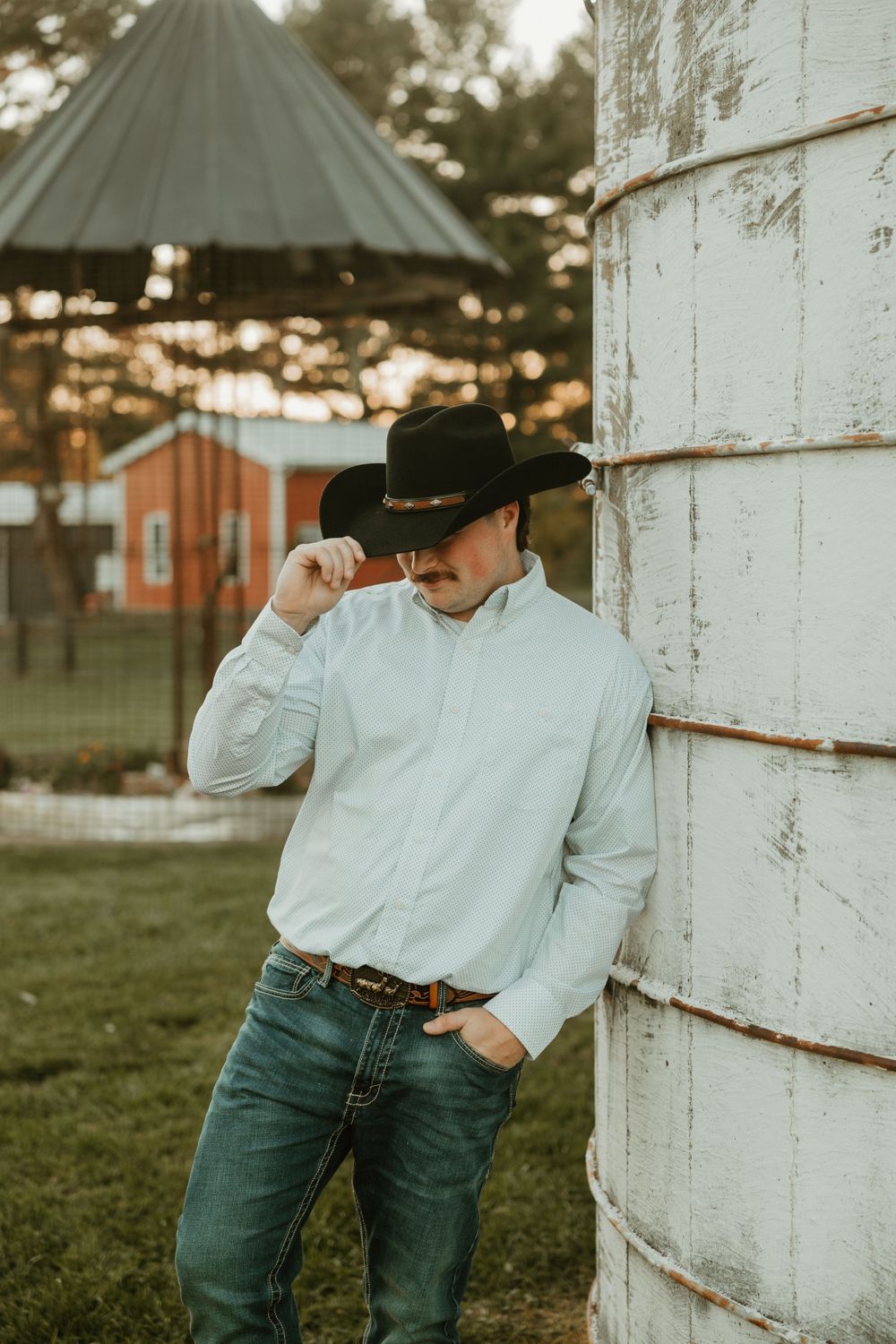 A person in western wear poses against a white wooden wall in artistic shots.