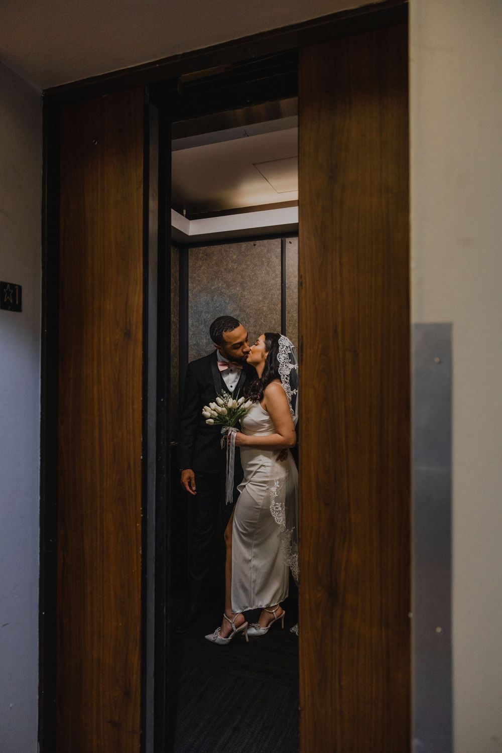 Couple shares romantic moment in dimly lit doorway during wedding photoshoot.