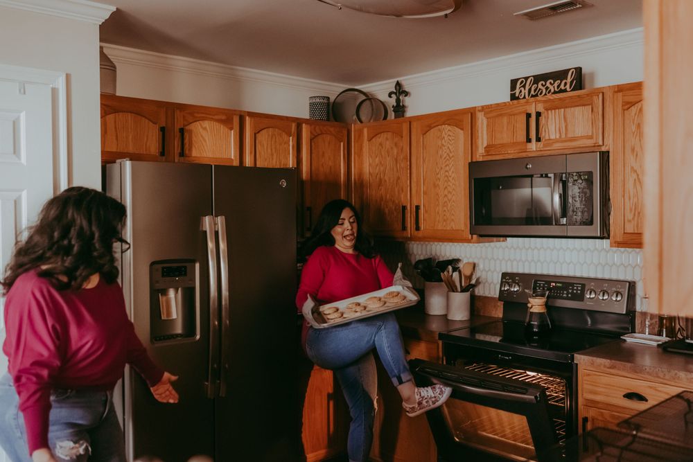 mother and adult daughter taking out cookies from oven, documentary family photography, Whitney Popp
