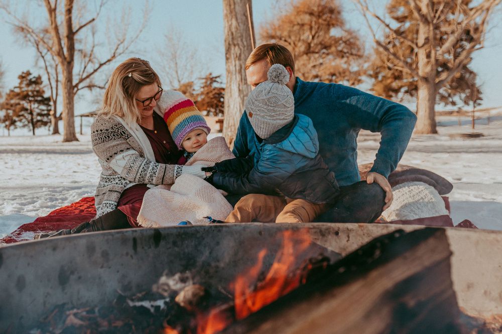 family cuddled together near fire outdoors with snow, documentary photography, Whitney Popp photographer.