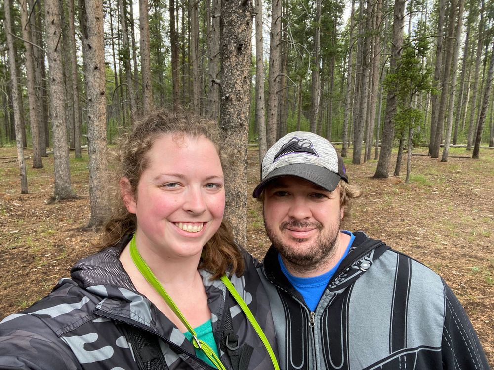 Two people enjoying a hiking adventure in a pine forest.