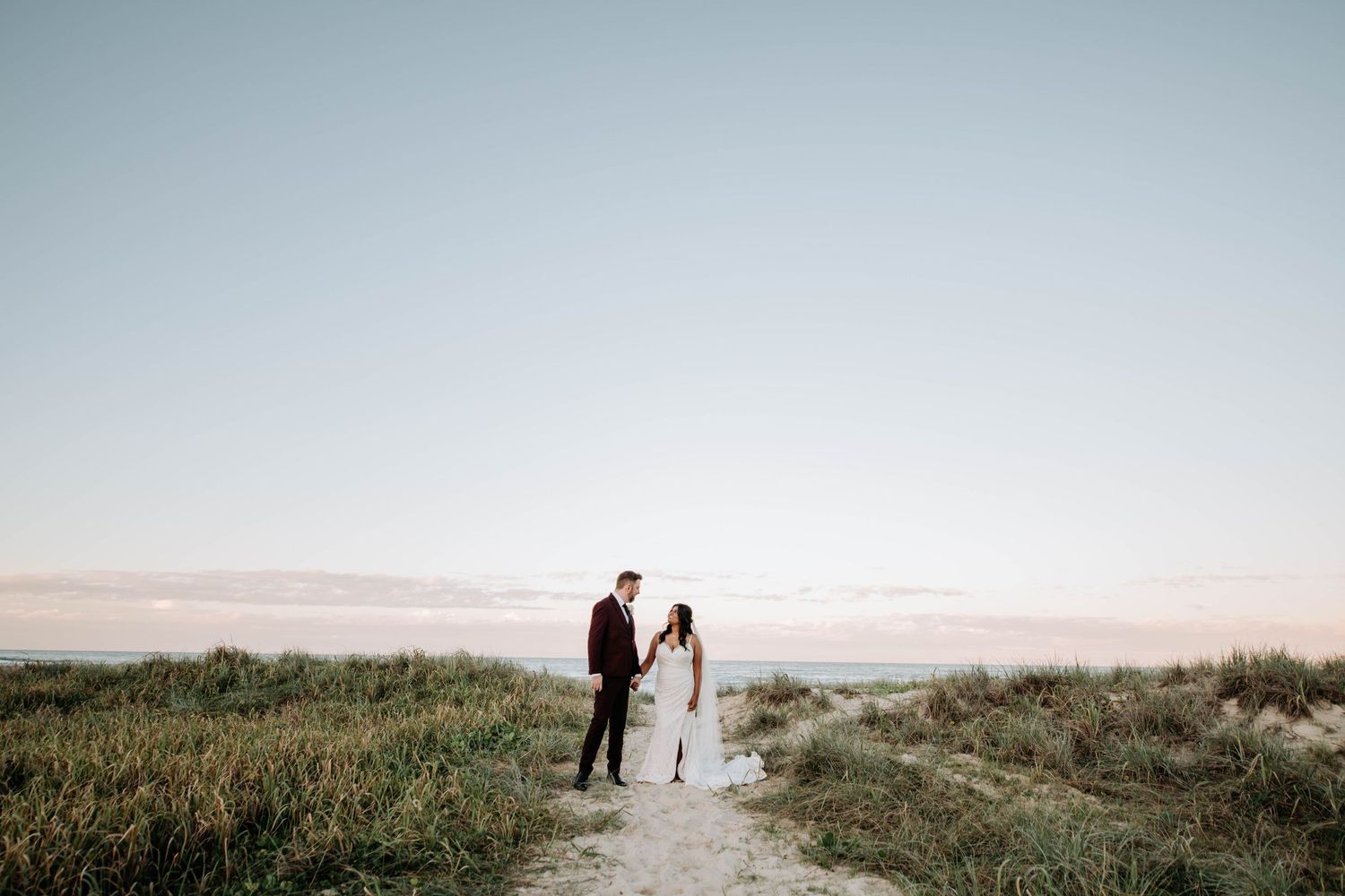 A couple walks hand in hand along a scenic path against a misty mountain backdrop.