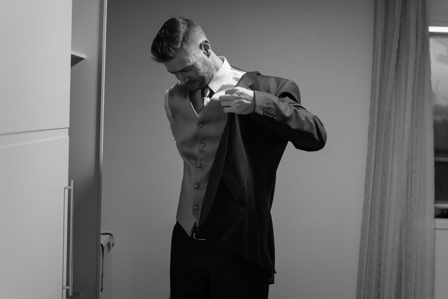 Black and white image of someone adjusting formal attire in preparation.