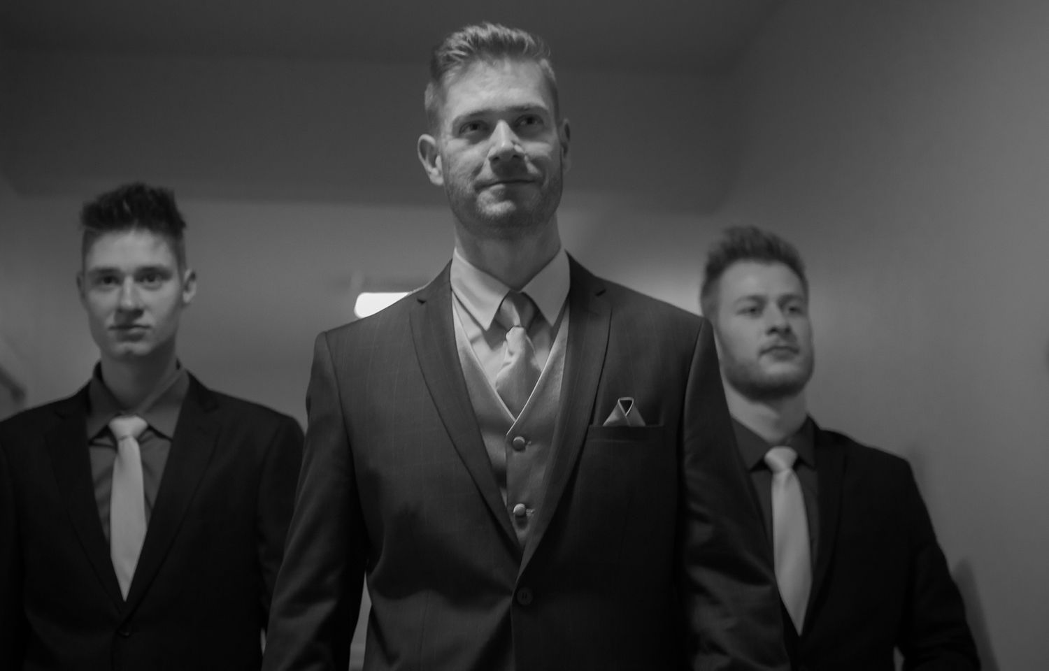 Three men in formal suits stand together in black and white photograph.