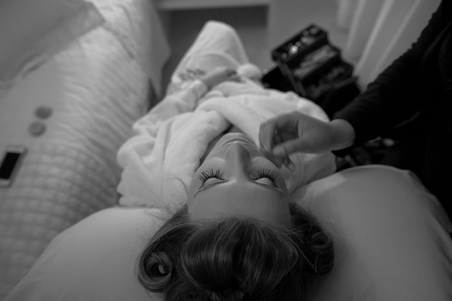Black and white close-up of a person lying down with engagement ring visible.
